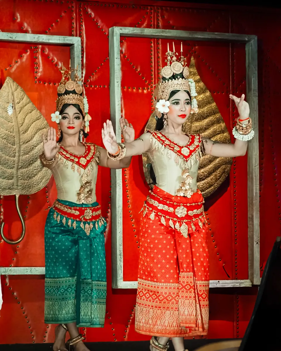 Two Apsara dancers in red and green costumes performing in Siem Reap