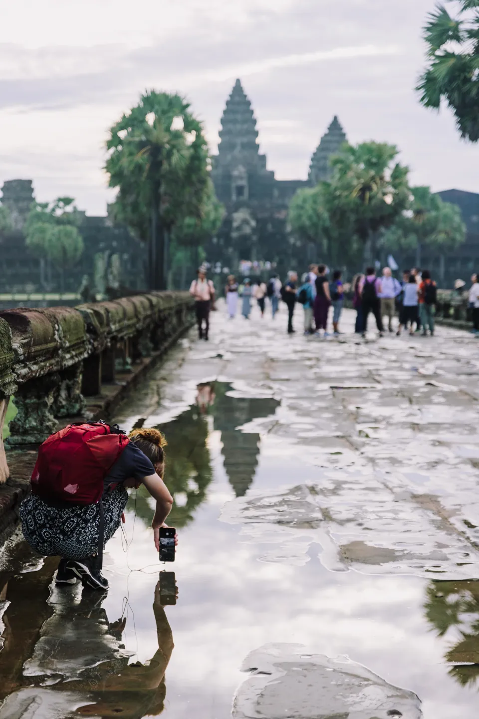 Visitors photograph reflections on Angkor Wat’s wet causeway.