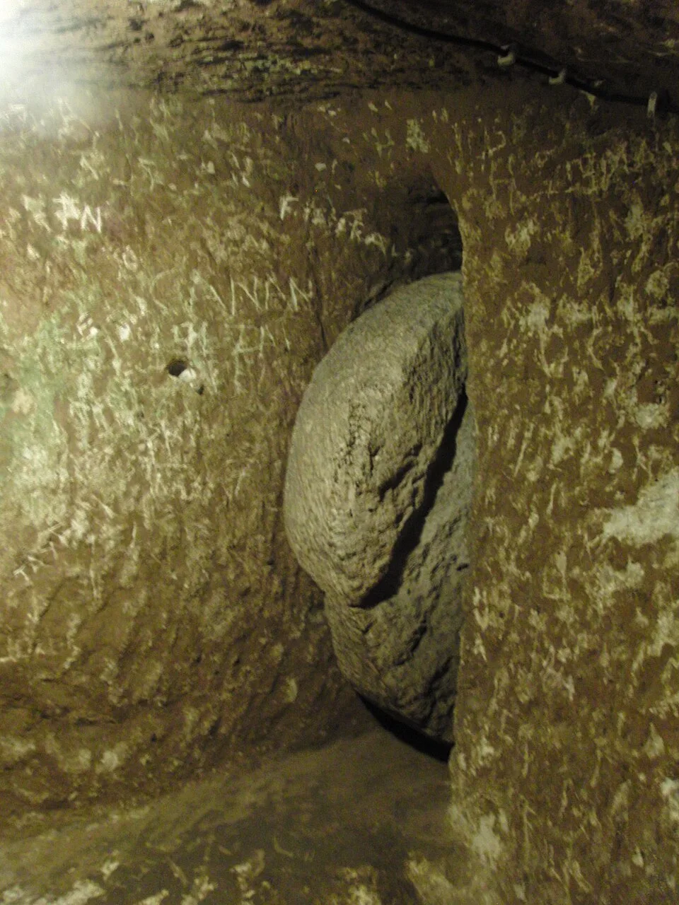 Round stone barrier beside a narrow opening in Derinkuyu