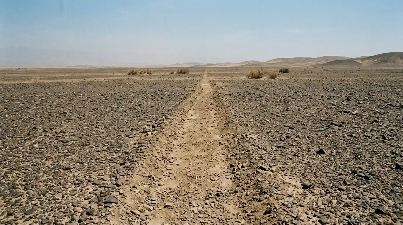 Interpretive AI-created illustration of a shallow pale trench through dark desert stones running to the horizon, illegible as a shape from ground level