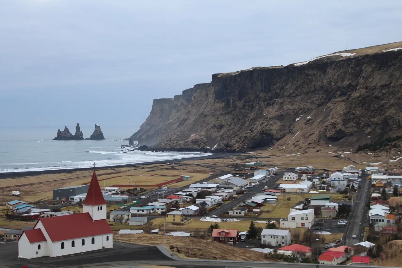 Vík's church, houses and the coast with Reynisdrangar in the distance